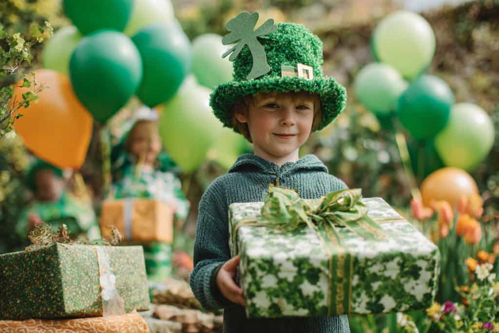 St Patricks decor of green balloons and green and white presents on a table for the party.